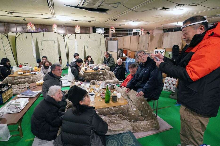 「スーパーもとや」の店内に設けられた宿泊スペースで、こたつに入ってくつろぐ「ワイズメンズクラブ」のメンバー＝28日午後、石川県輪島市町野町（恵守乾撮影）