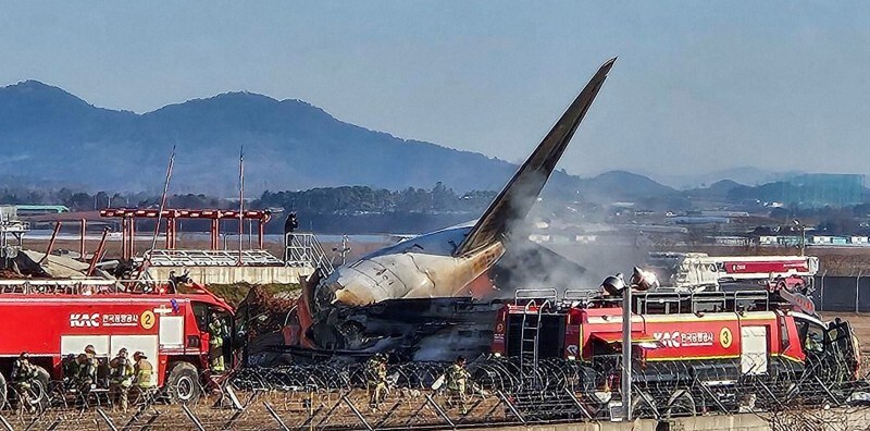 旅客機の炎上現場で消火作業に当たる消防隊員ら＝韓国南西部の務安国際空港で2024年12月29日、聯合・ロイター