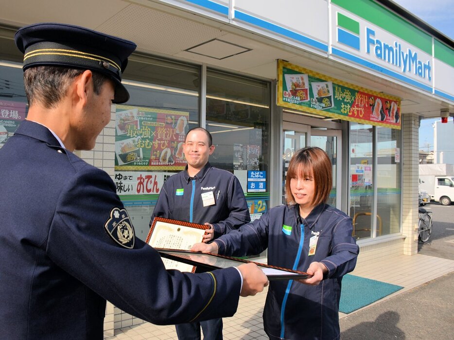 感謝状を受け取る藤本さん（右）と、店への感謝状を手に見守る辻本さん（奥）＝城陽市枇杷庄・ファミリーマート城陽枇杷庄店