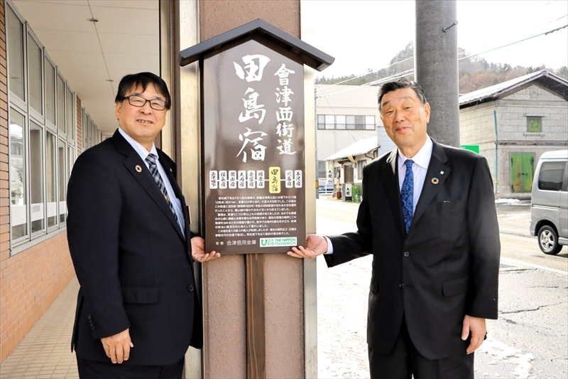 看板を披露する添田理事長（右）と渡部町長