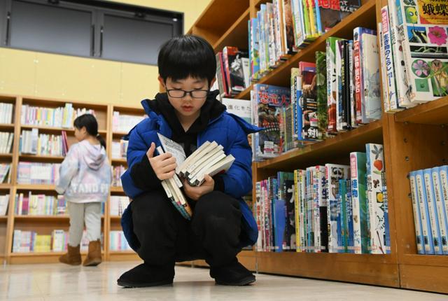 たくさんの気になる本を抱える子どもたち=2024年12月21日午前10時10分、石川県輪島市、小宮健撮影