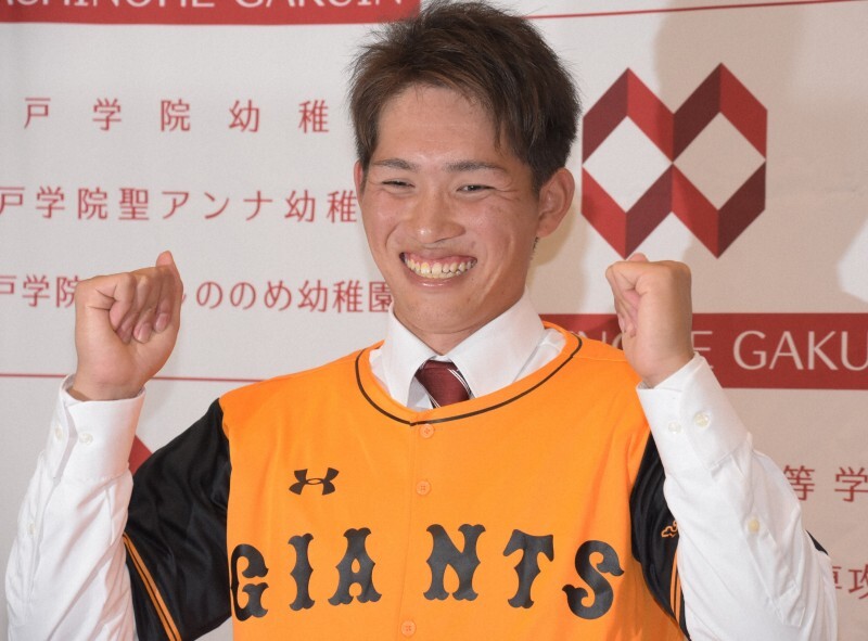 プロ野球のドラフト会議で1位指名された巨人のユニホームを着て写真撮影に応じる八戸学院大の高橋優貴投手＝青森県八戸市の八戸学院大で2018年10月25日、一宮俊介撮影