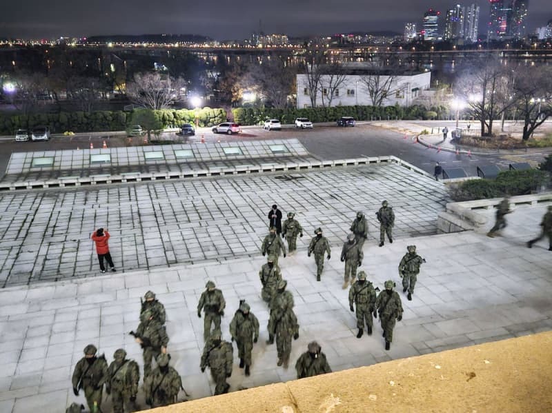 １２月４日、韓国国会敷地内で出入り口に向かう軍人たち＝ソウル（共同）