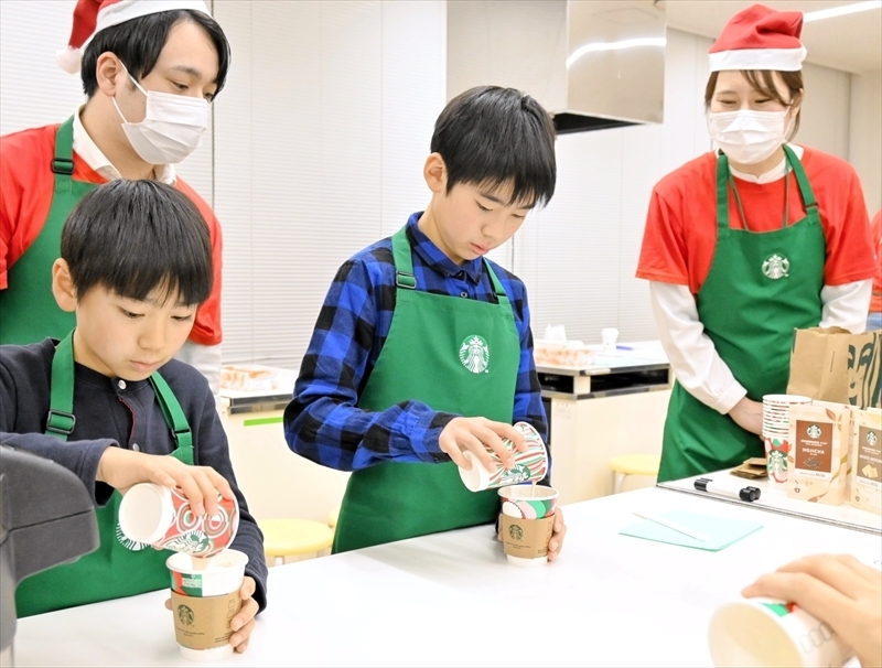 泡立てた牛乳を注いで飲み物を仕上げる子どもたち