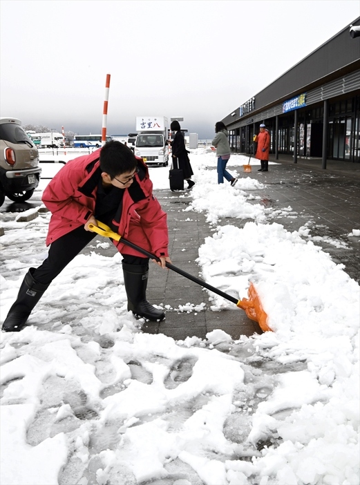 今シーズン初の積雪となり、道の駅猪苗代施設周辺の雪かきに追われる従業員＝３０日午前９時１５分ごろ