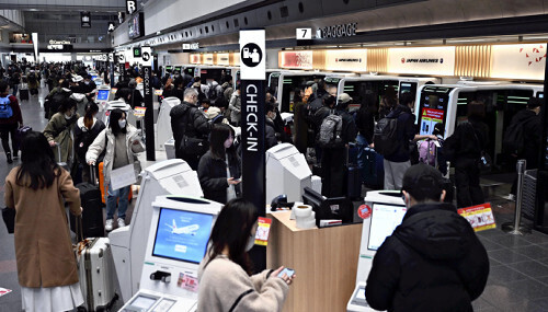 日本航空の自動チェックイン機や自動手荷物預け機に並ぶ人たち（２６日午前、羽田空港で）＝武藤要撮影