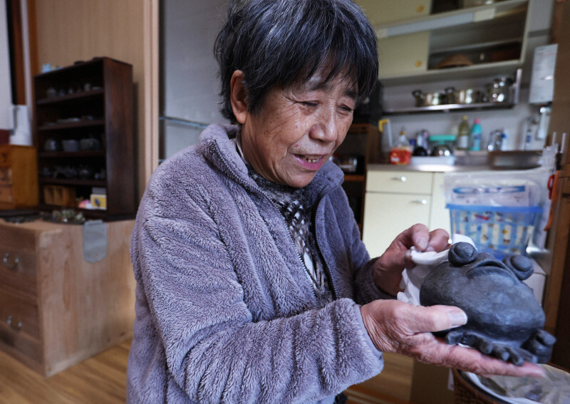 能登半島地震から1年を前に避難所から珠洲市内の新居に入居した藪信子さん。趣味の珠洲焼を並べ、「ちょっと指が欠けちゃったんだけど、無事でよかった」とほっとした表情を浮かべた＝石川県で2024年12月30日、滝川大貴撮影