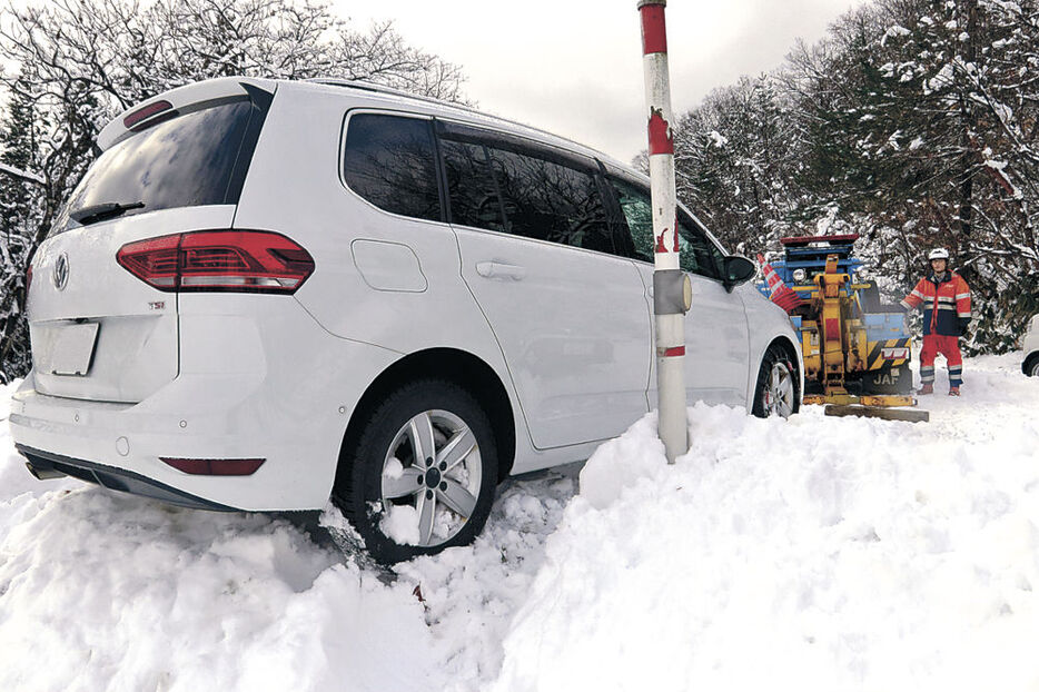 雪で段差に気付かず脱輪した乗用車。隊員がワイヤで引っ張り上げた＝２３日午後０時半、南砺市才川七