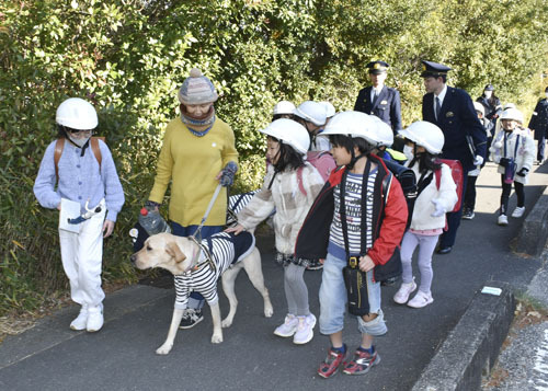 【児童の下校を見守る中西副会長（左から2人目）と隊員犬＝津市久居西鷹跡町で】