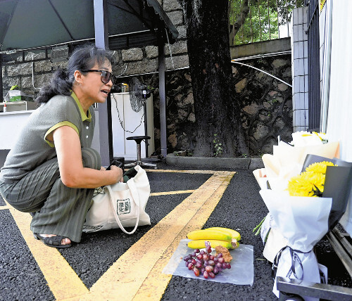 ２５日、中国・深セン日本人学校で花と果物を供える女性＝鈴木隆弘撮影