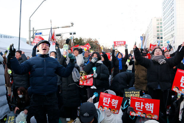 弾劾案が可決され国会議事堂前で喜ぶ人たち＝14日、ソウル（ＮＮＡ撮影）