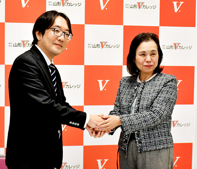 併修に向けて握手を交わす山形Ｖ．カレッジの山本絵里子校長（右）と開志創造大学の担当者＝山形市・同校