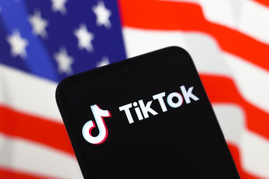 2024年11月18日、スマートフォンの画面にソーシャル・ネットワーク「TikTok」のロゴが表示。背景には星条旗 - 写真提供＝Jaque Silva／NurPhoto／共同通信イメージズ