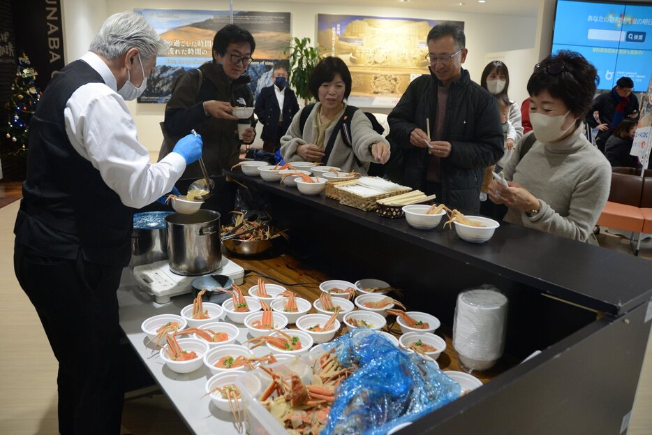 親がに汁を受け取る観光客ら＝７日、鳥取市湖山町西４丁目の鳥取砂丘コナン空港