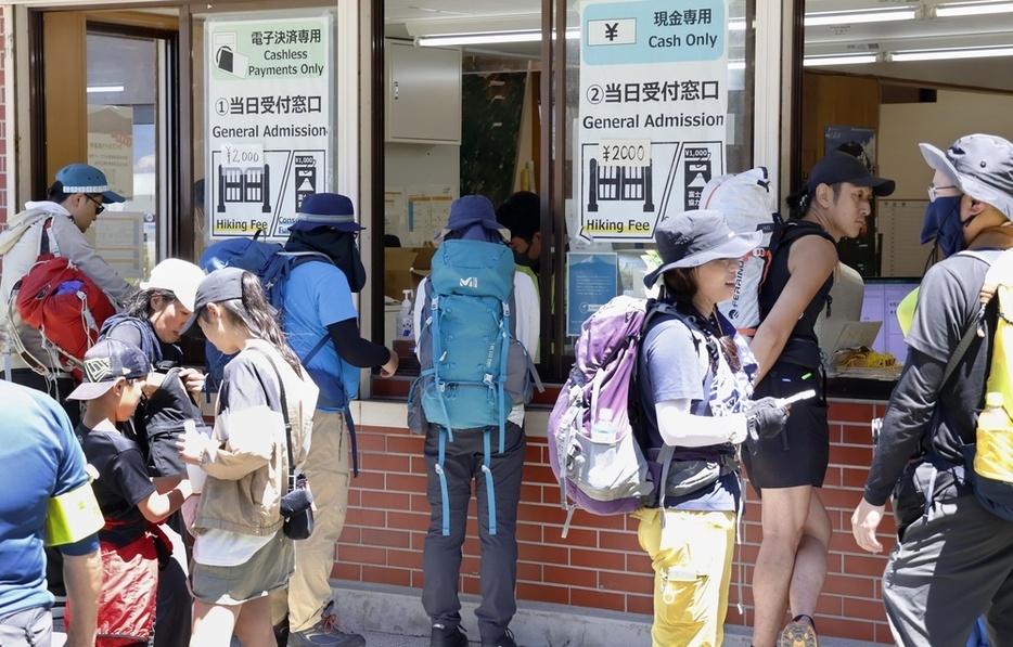 8月、富士山の山梨県側登山道「吉田ルート」の5合目で規制ゲートの受付に並ぶ登山客