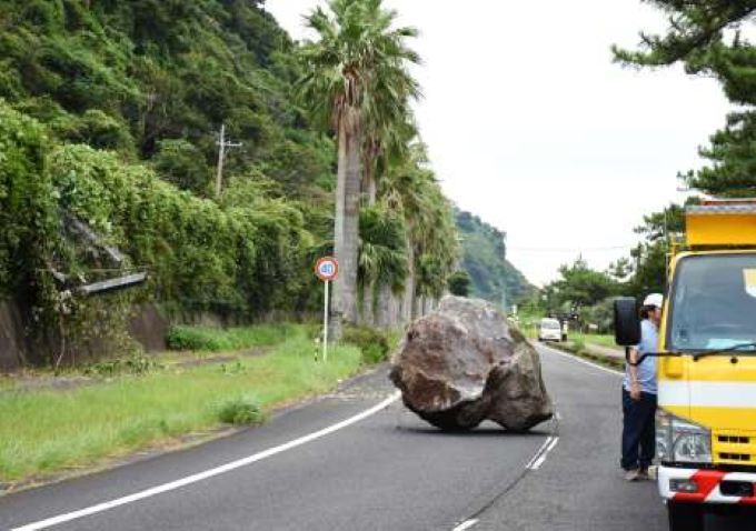 鹿児島県内で最大震度５強を観測した８月の地震で、フェンスを突き破って落下し、県道をふさぐ岩＝指宿市東方