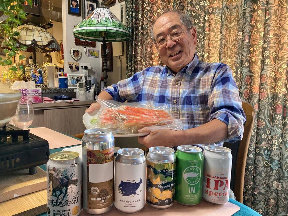 並んだビールを前にタラバガニを持って笑顔の斎藤克己カメラマン