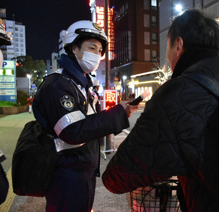 自転車の飲酒運転の取り締まりで呼気検査を実施する警察官＝福岡市中央区天神で２０２４年１２月１３日午後８時５１分、栗栖由喜撮影