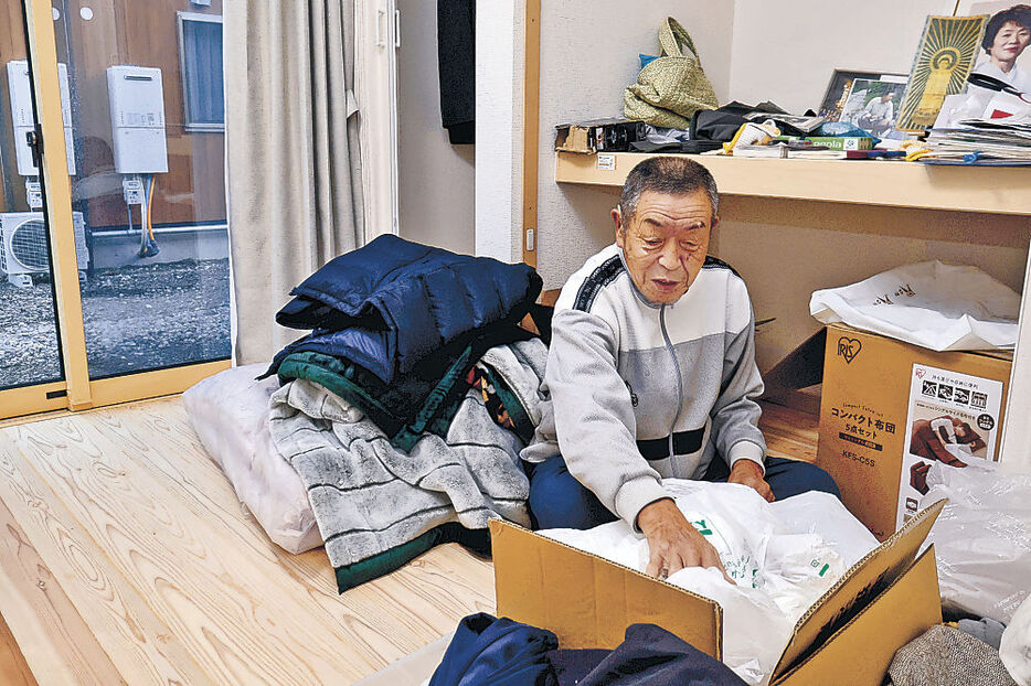 荷物を部屋に運び込み片付けをする則貞さん＝珠洲市大谷町