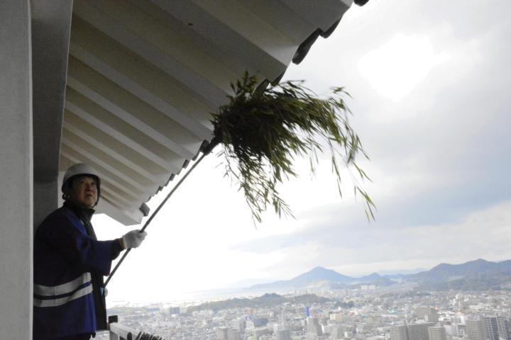 ササぼうきで天守軒下のほこりを落とす参加者＝18日午前、松山市丸之内