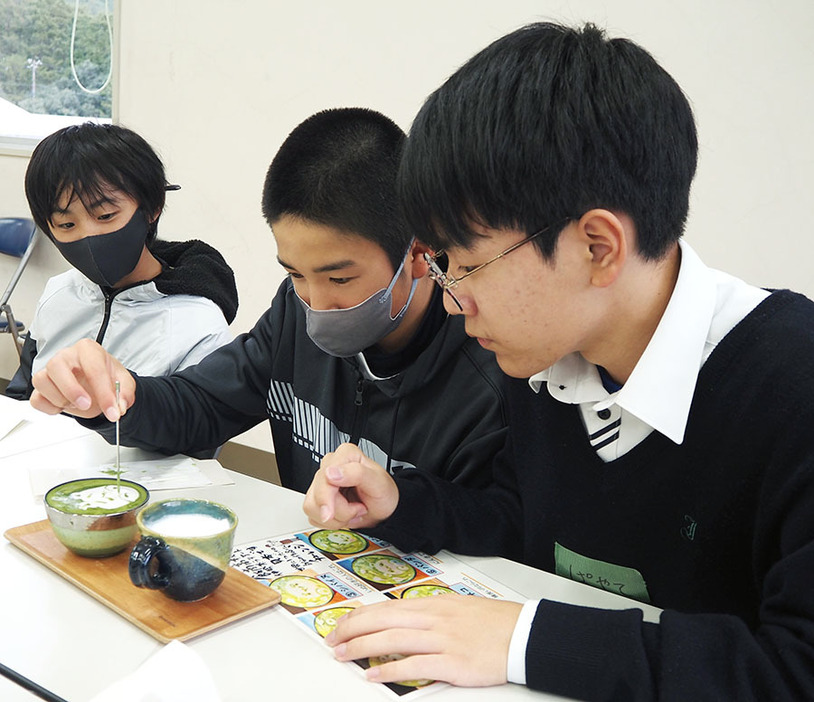 美術部員（右）のアドバイスを受けて緑茶ラテアートを作る児童＝飯南町粥見の飯南高で