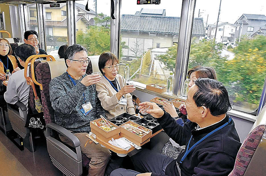 列車内で加賀料理とともに地酒を味わう参加者