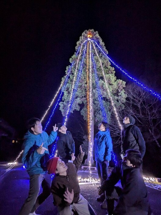 試験点灯し、暗闇に浮かぶクリスマスツリーを見上げる関係者たち＝三重県名張市赤目町長坂で２０２４年１２月４日午後５時４８分、久木田照子撮影