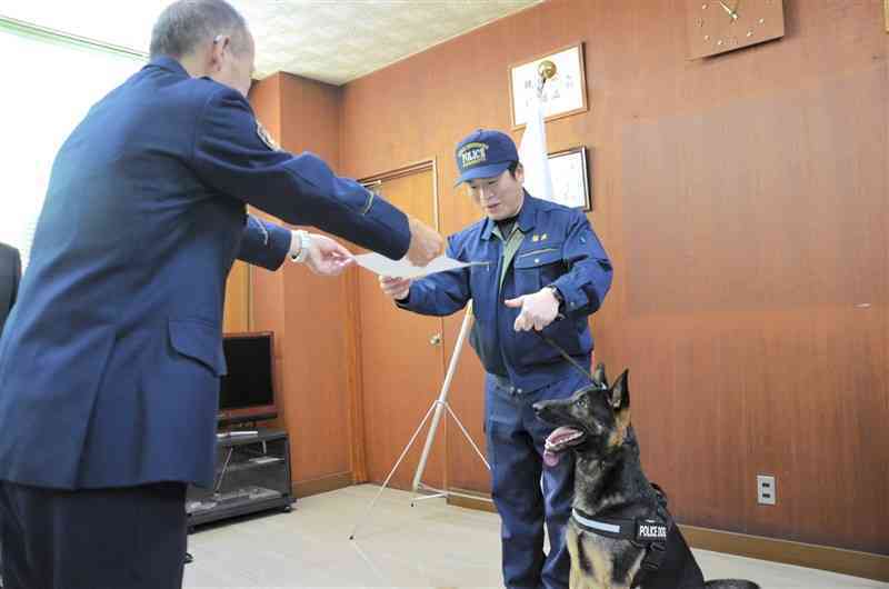 髙橋太玉名署長（左）から表彰状を受け取る警察犬のジゲン号と指導士の井野満宏さん＝6日、玉名市