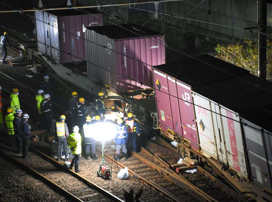 脱線した貨車をレールに戻す作業をする作業員ら＝１４日午後６時ごろ、薩摩川内市の川内駅