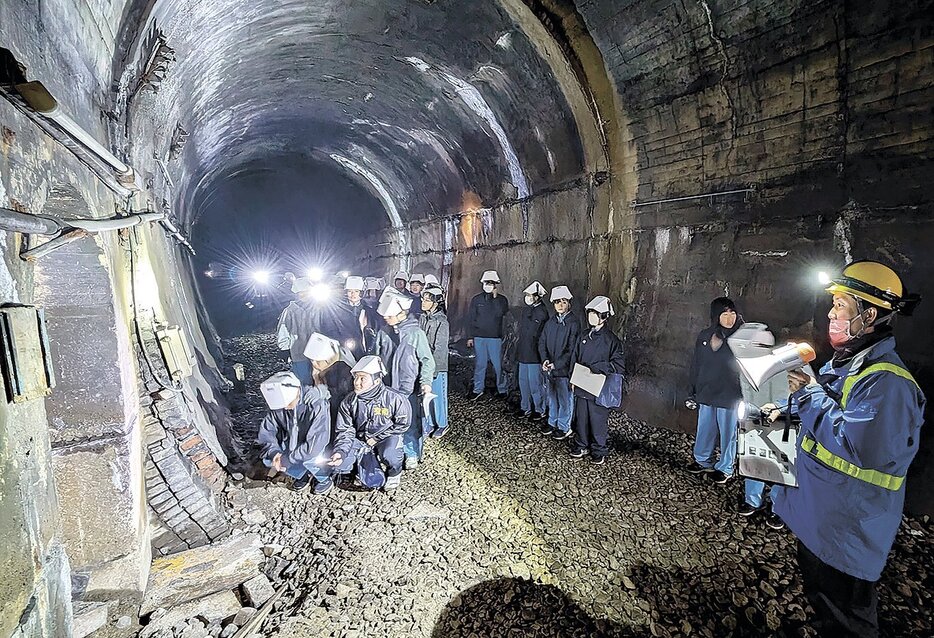 JRの社員から説明を受けながら篠ノ井線の古いトンネルを巡る生徒たち