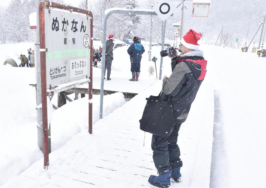 糠南駅のホームで記念写真を撮るクリスマスパーティーの参加者＝2023年12月