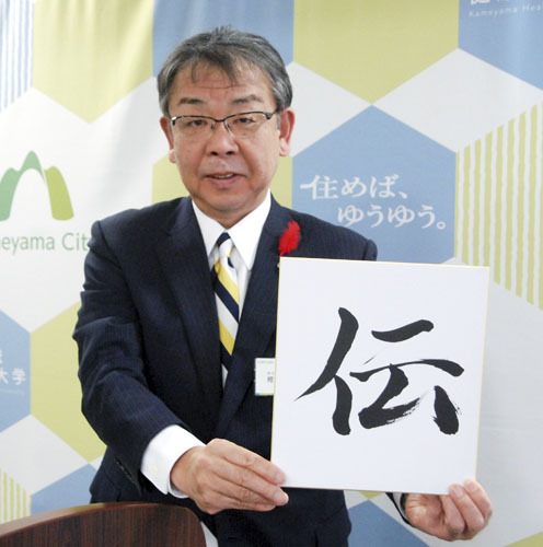 【今年の漢字1字「伝」を掲げる櫻井市長＝亀山市役所で】