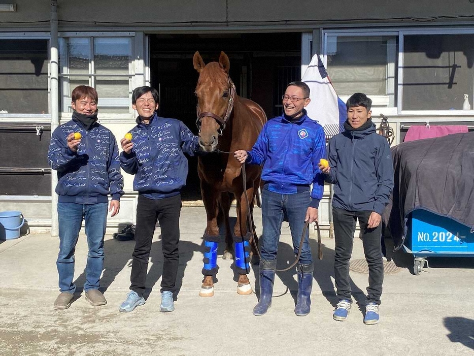 田中博師（右）、田端助手（右から2人目）ら厩舎スタッフと記念撮影をするレモンポップ