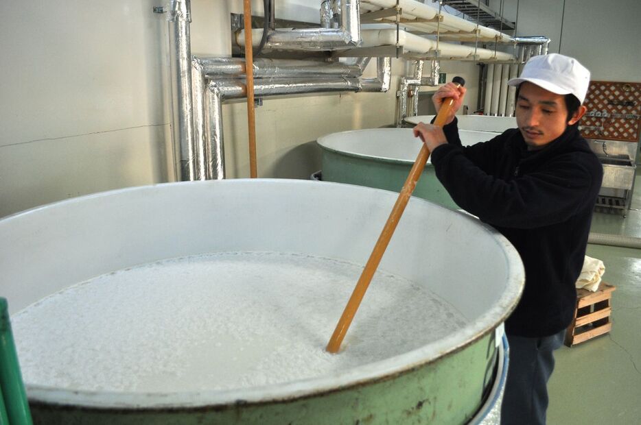 日本酒の仕込み作業。タンクに仕込んだもろみをかき回す杜氏（とうじ）＝福島県喜多方市の大和川酒造店（2015年撮影、時事）