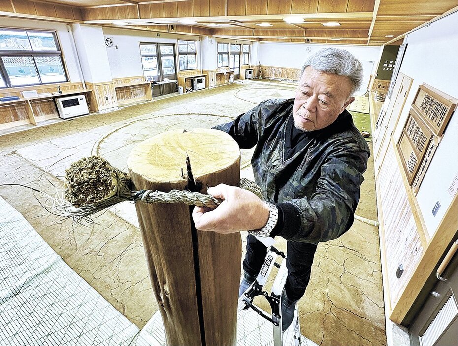 土俵脇にある鉄砲柱にしめ縄を掛ける中田さん