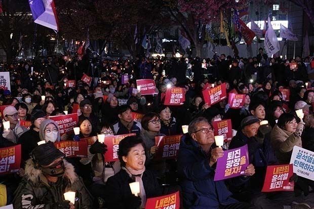 光化門交差点に集まった野党支持者ら。ろうそくを片手に尹氏の退陣を求めた＝４日、韓国・ソウル（ＮＮＡ撮影）