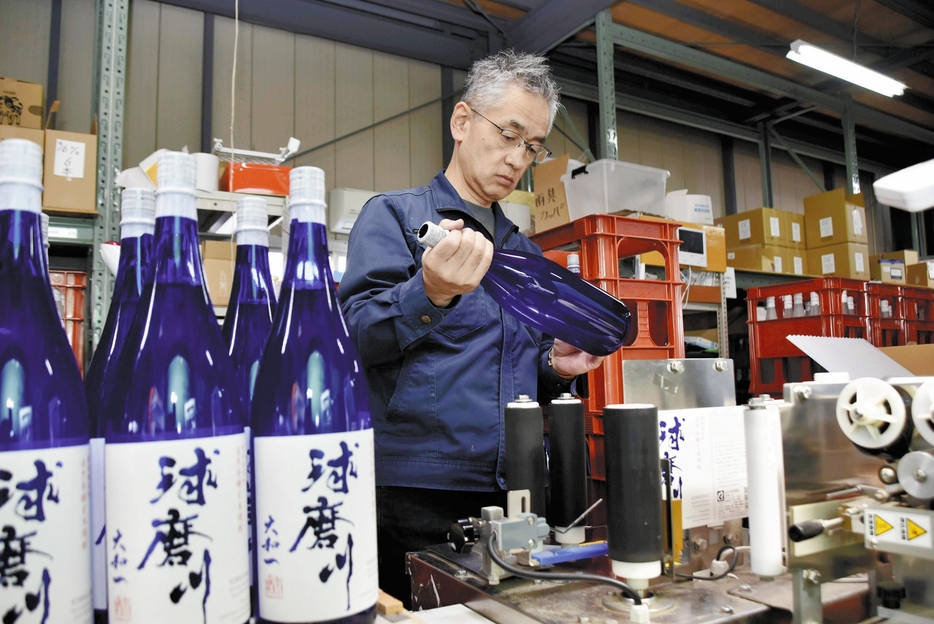 瓶に詰めた酒の状態を確認する大和一酒造元の下田文仁社長（熊本県人吉市で）＝井上裕介撮影