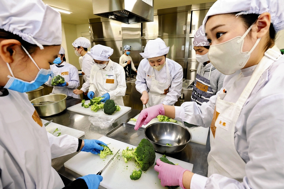 被災地で炊き出しした料理を高校生たちに教える学生（右）ら（11月30日、福岡市城南区の中村学園大で）＝秋月正樹撮影