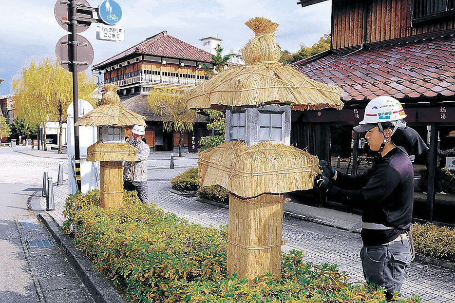 石燈籠にこもを掛ける職人=加賀市山代温泉