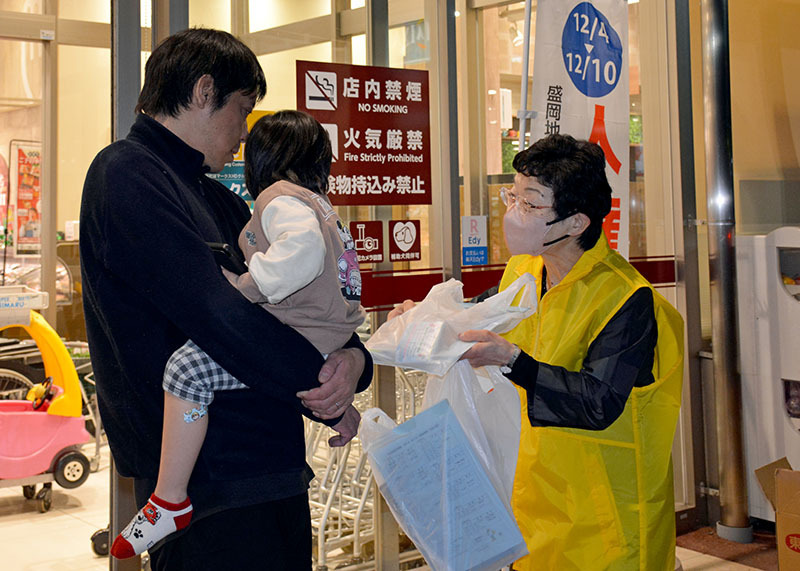 一関市花泉町で買い物客に関連グッズを配り、人権週間実施を周知する人権擁護委員（右）