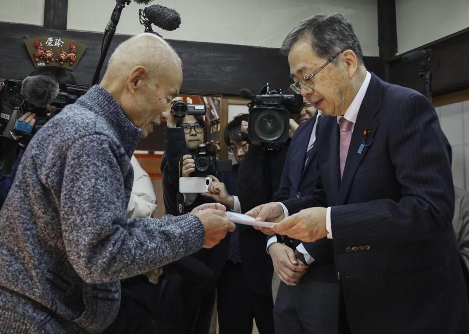 被団協代表委員の箕牧智之さん（左）から要望書を受け取る公明党の斉藤代表＝1日午前、広島県北広島町