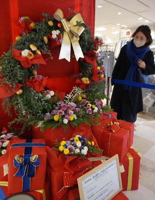 大阪府東大阪市産のキクが飾り付けられたクリスマスリースに見入る女性＝同市の近鉄百貨店東大阪店