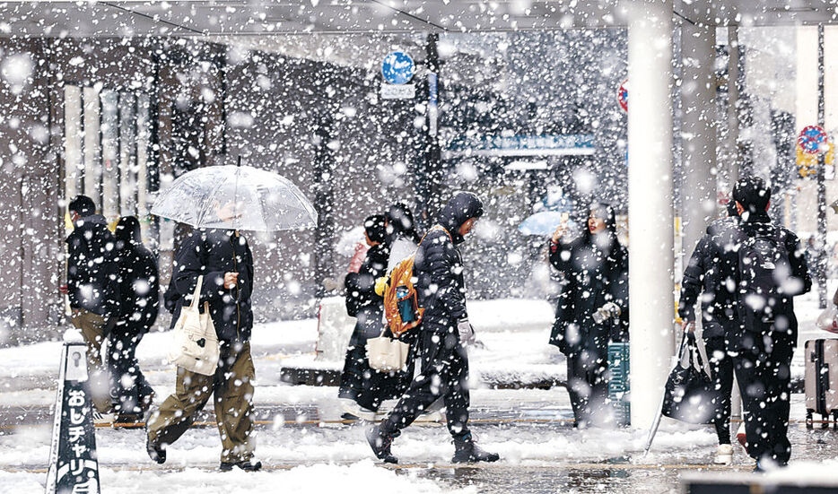 降りしきる雪の中を歩く人＝２８日午前１０時半、富山駅前