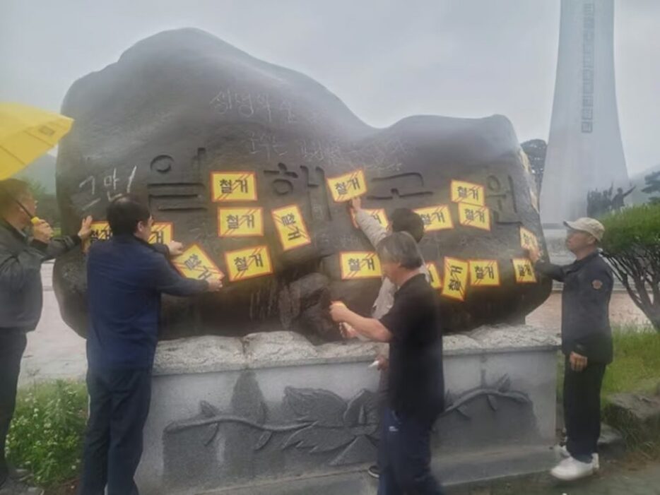 「日海公園」表碑に撤去ステッカーを貼付した「生命の森を取り戻す陜川郡民運動本部」メンバー(c)NEWSIS