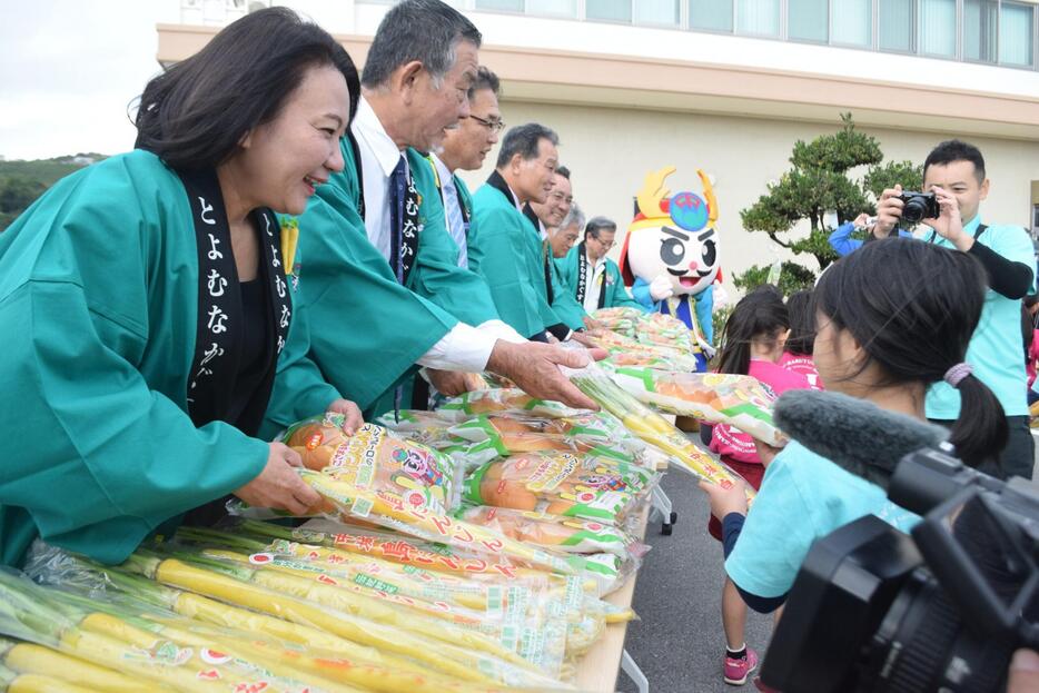 旬入りした村特産の島ニンジンなどを園児らに手渡す比嘉麻乃村長（左端）ら＝12日、中城村役場