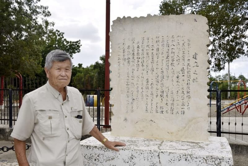 日本人移住者の歴史が記された石碑の前に立つ向井猛さん＝２０２３年８月、ドミニカ共和国ダハボン（共同）