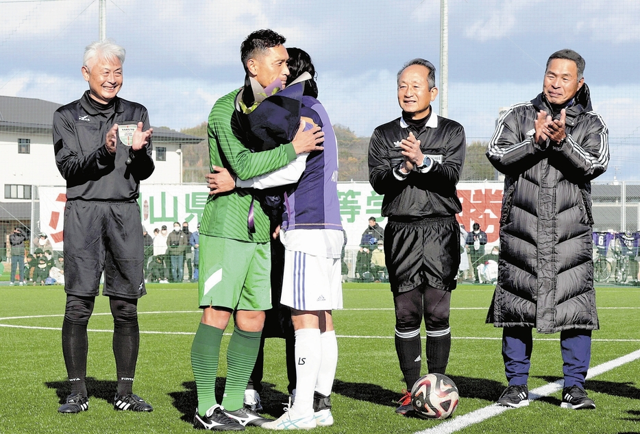 水島工OBと抱き合って健闘をたたえ合う青山さん（左から2人目）（岡山県倉敷市で）