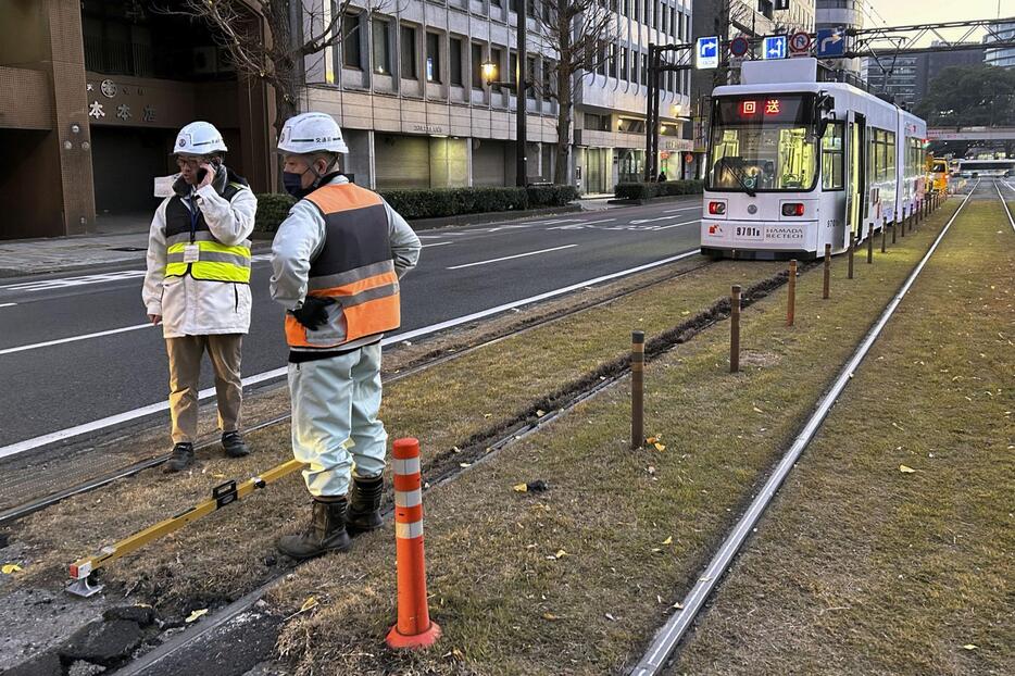 路面電車が脱線した現場付近を調べる熊本市交通局の職員ら＝31日午後5時34分、熊本市中央区