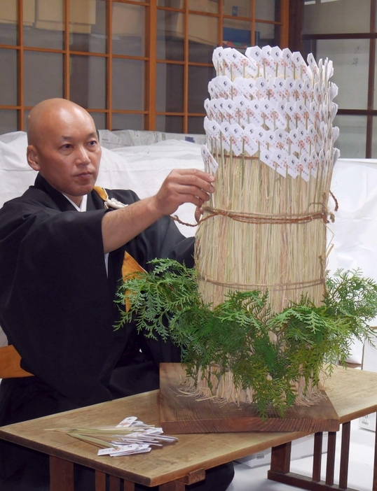 竹串に挟んだお札をわら束に差す僧侶=25日、奈良市五条町の唐招提寺