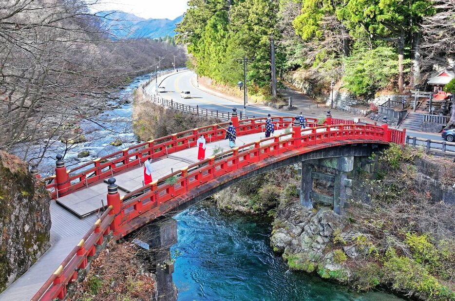 神職と八乙女によってすすが払われる神橋＝12日午前10時25分、日光市上鉢石町、ドローンから